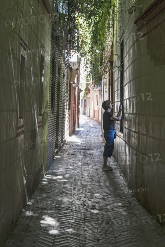 Spain, Seville, Woman taking photo with cell phone in backstreets of Judeira