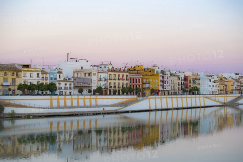 Spain, Seville, Colorful residential building reflecting in Guadalquivir river