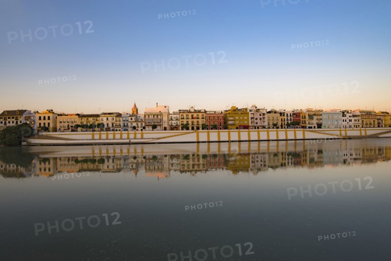 Spain, Seville, Colorful residential building reflecting in Guadalquivir river
