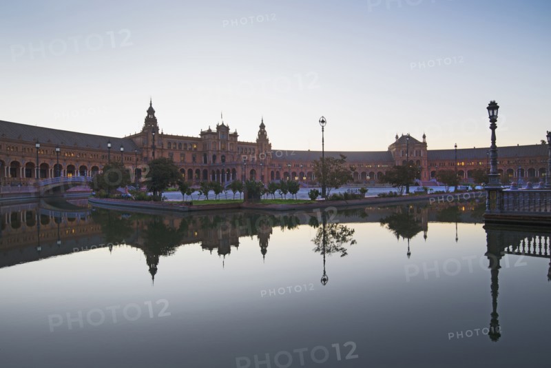 Spain, Seville, Plaza De Espana reflecting in pond at dawn