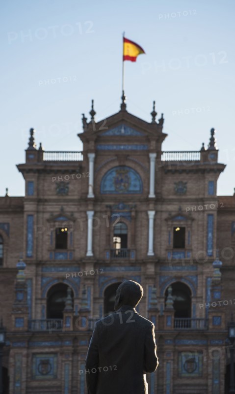 Spain, Andalusia, Seville, Facade with spanish flag and statue of Anibal Gonzales in Plaza de Espana