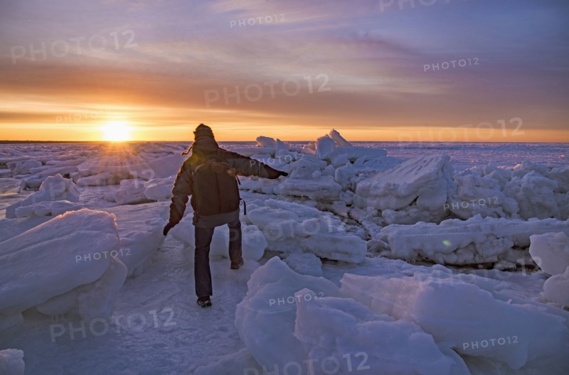 USA, Massachusetts, Cape Cod, Eastham, Man balancing on sea ice at dusk