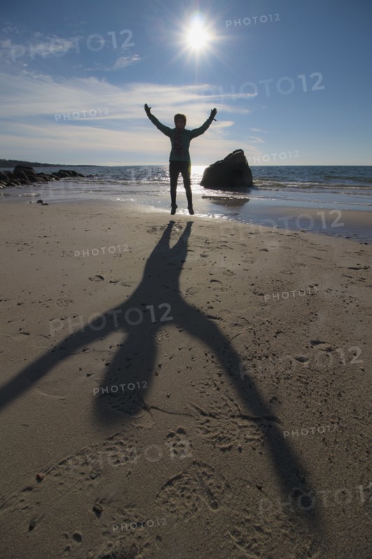 Silhouette of senior woman jumping on beach