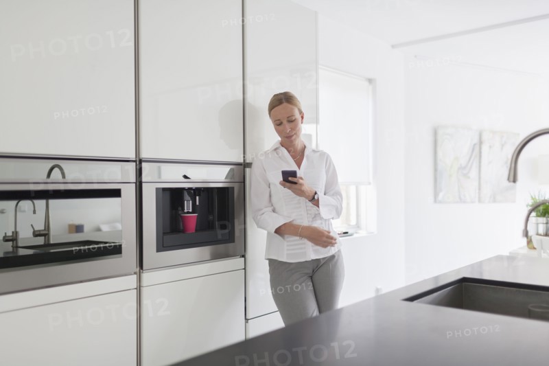 Woman using phone in kitchen