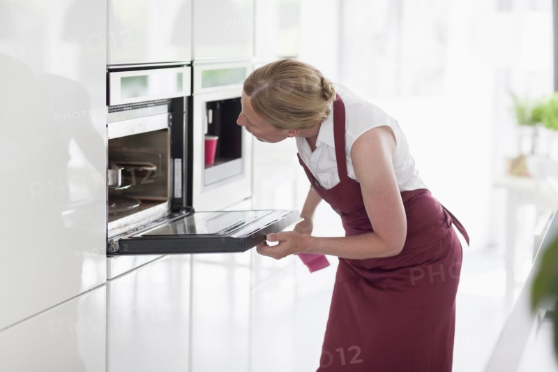 Woman using oven in kitchen