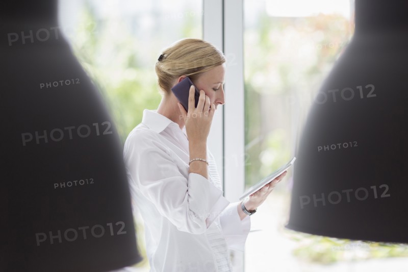 Woman talking on phone and using digital tablet
