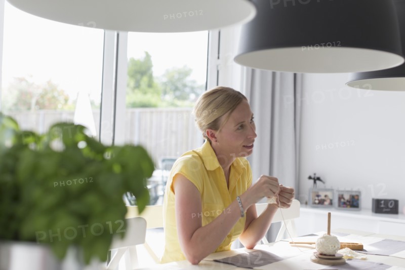 Mature woman making macrame at table