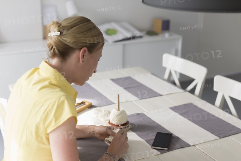 Mature woman making macrame at table