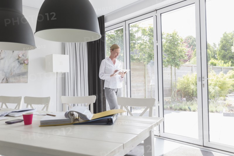 Mature woman working with mobile devices in modern living room