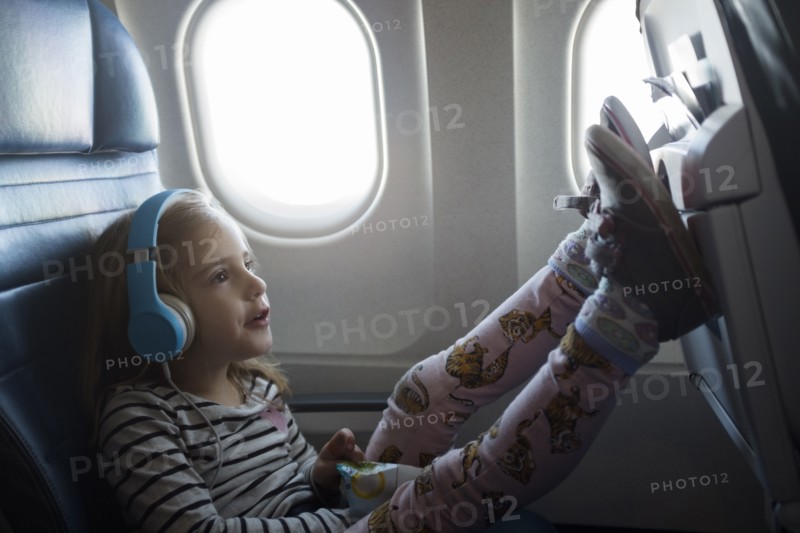 Girl wearing headphones on airplane