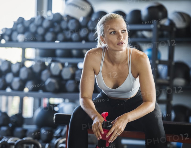 Young woman holding bottle in gym