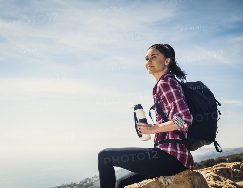 Woman with water bottle sitting on rock