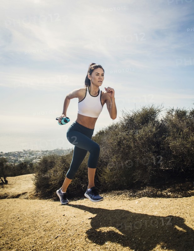 Woman jogging on mountain with water bottle