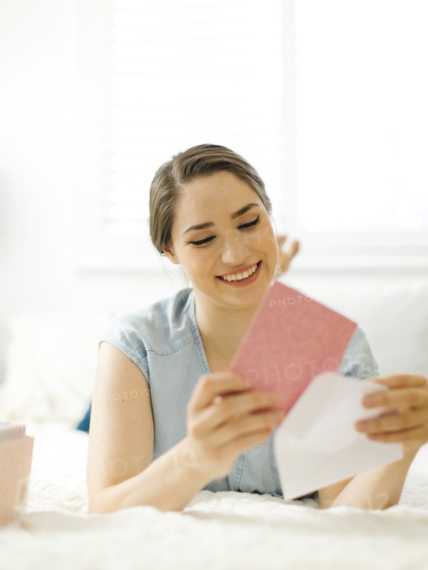 Woman putting card into envelope on bed
