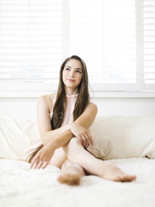 Young woman sitting on bed