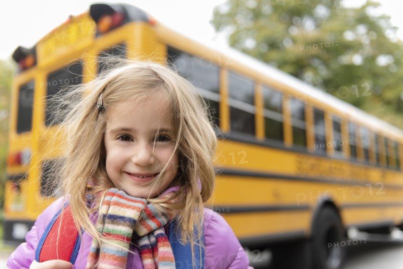 Smiling girl by school bus