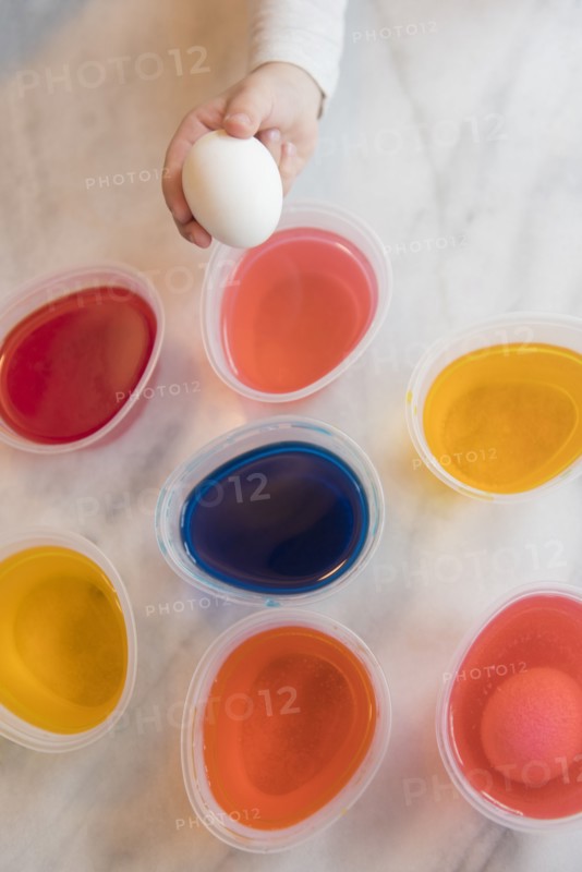Hand of girl selecting dye for Easter egg