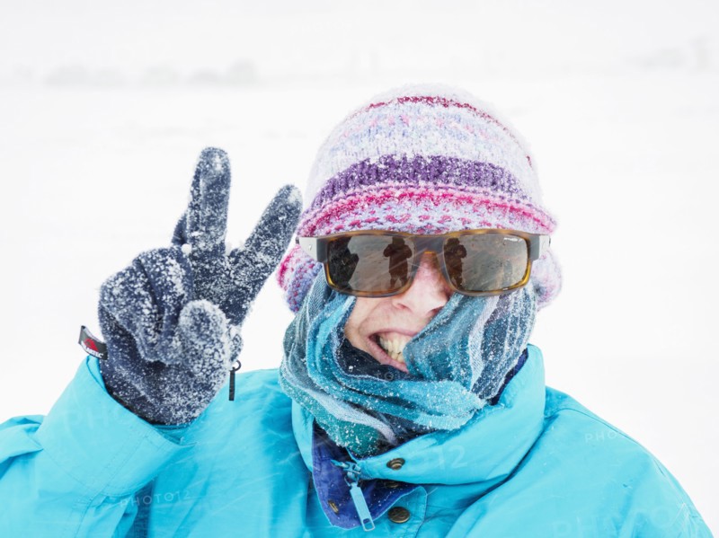 Smiling woman making peace gesture in snow