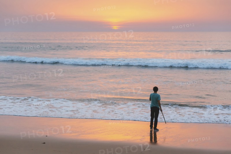 Young man on beach at sunset in Lisbon, Portugal