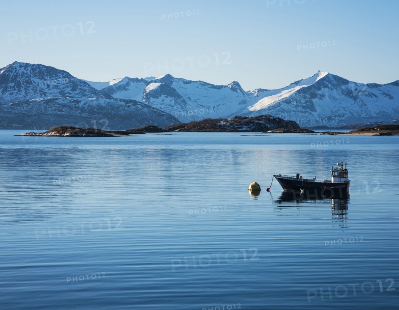 Fishing boat by snow covered mountains in Tromso, Norway