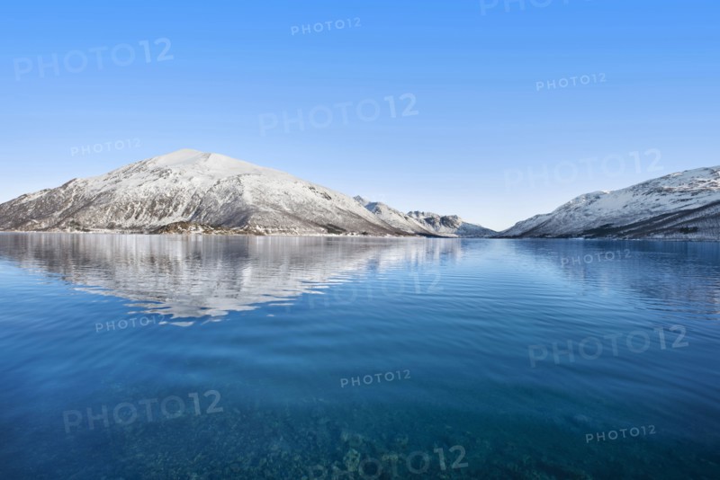 Snow covered hills by sea in Tromso, Norway