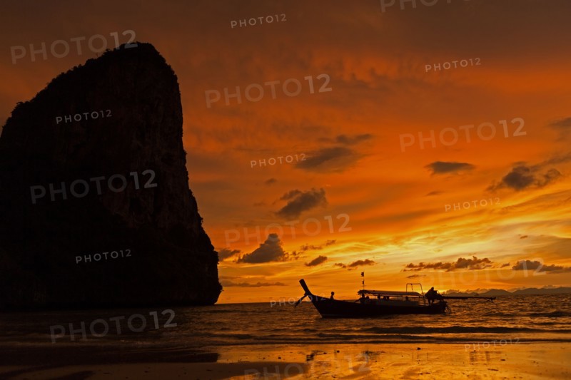 Silhouette of boat by cliff at sunset in West Railay, Thailand