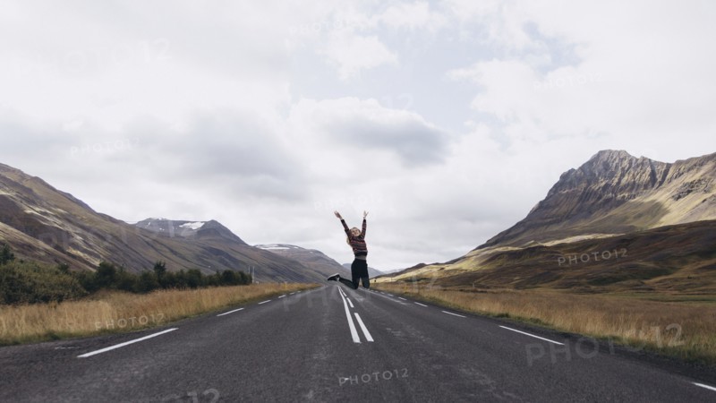 Woman jumping on highway in Iceland