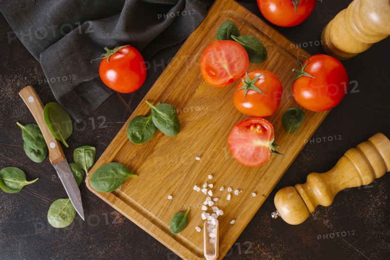 Tomatoes, basil and salt on wooden cutting board