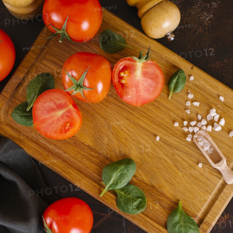 Tomatoes, basil and salt on wooden cutting board