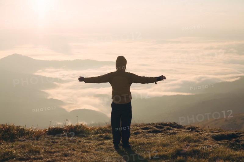 Man with arms outstretched in the Carpathian Mountain Range at sunrise