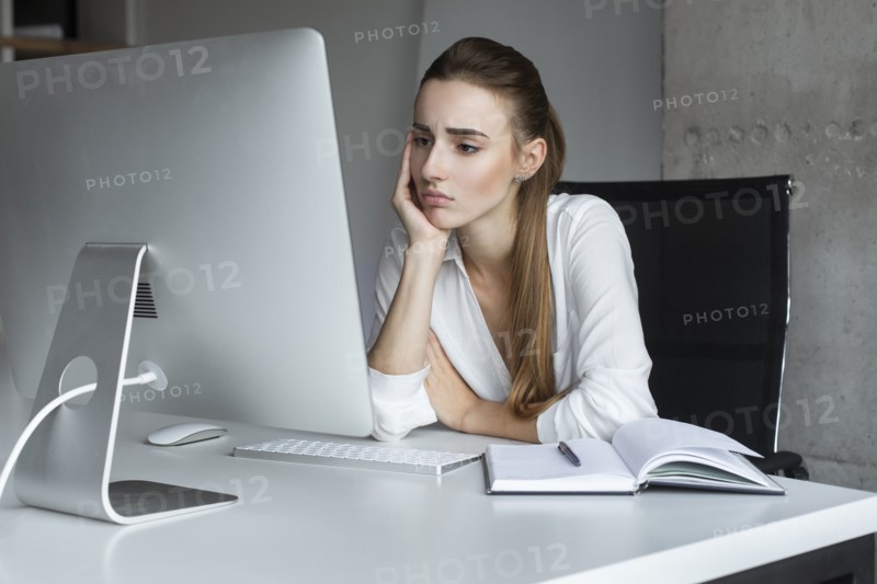 Depressed businesswoman working at desktop computer