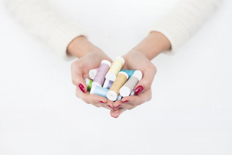 Hands of woman holding spools of cotton