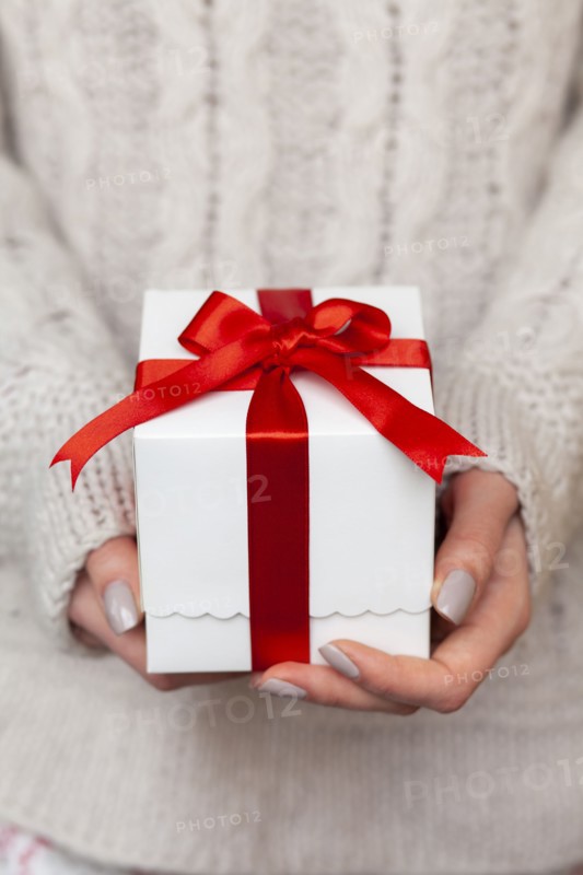 Hands of woman holding Christmas present with candy cane