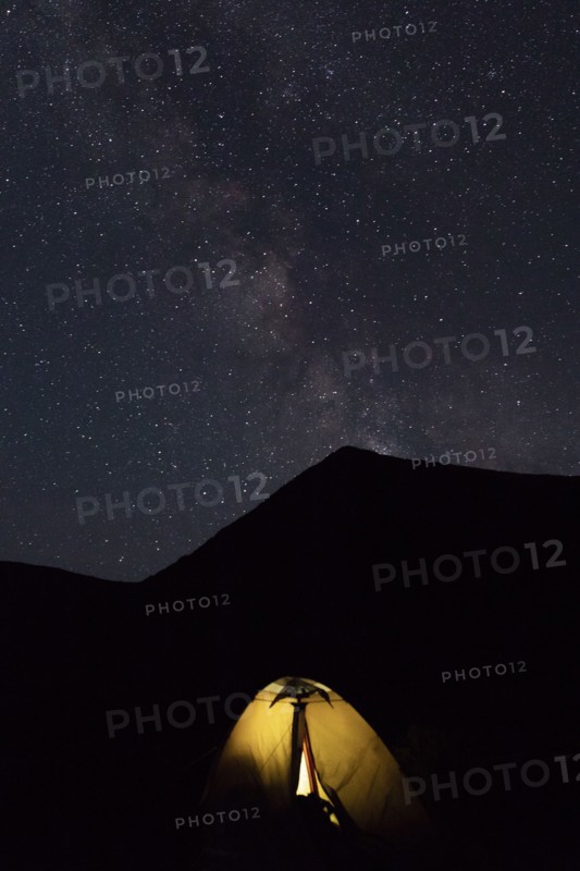 Illuminated tent by mountain at night