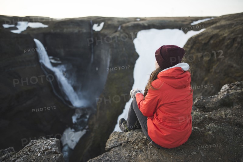 Hiker sitting on cliff by Haifoss waterfall in Iceland