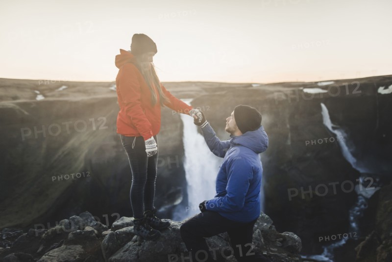 Young man proposing to his girlfriend while hiking by Haifoss waterfall in Iceland