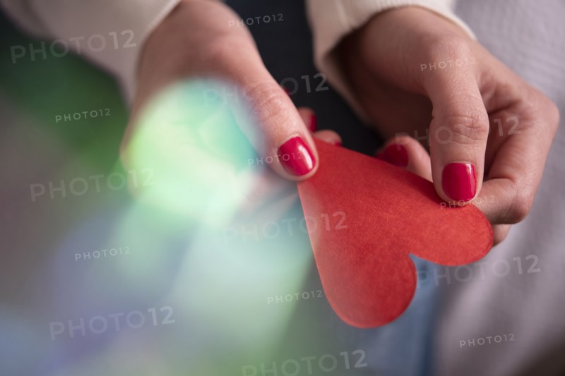 Hands of woman holding red paper heart