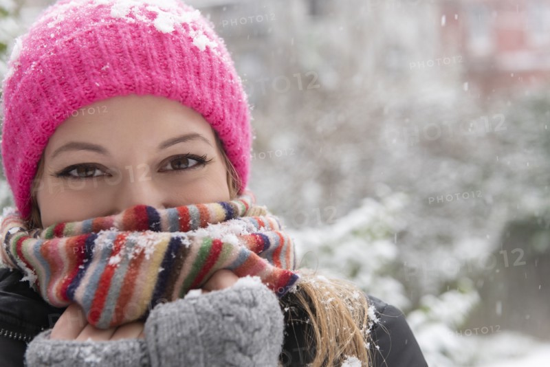 Portrait of young woman wearing woolly hat and scarf in snow