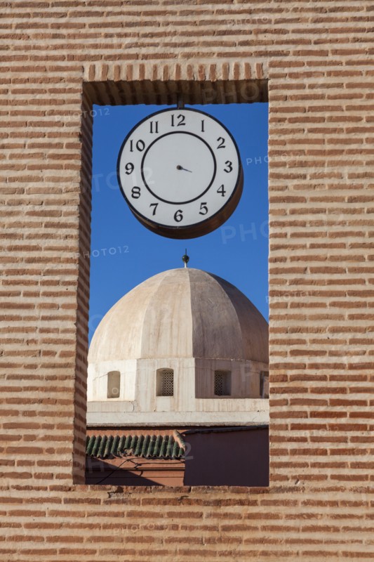 Dome behind brick window with clock in Marrakesh, Morocco