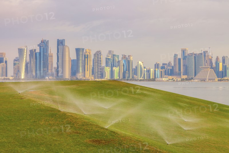 Sprinkler system on lawn by skyline of Doha, Qatar