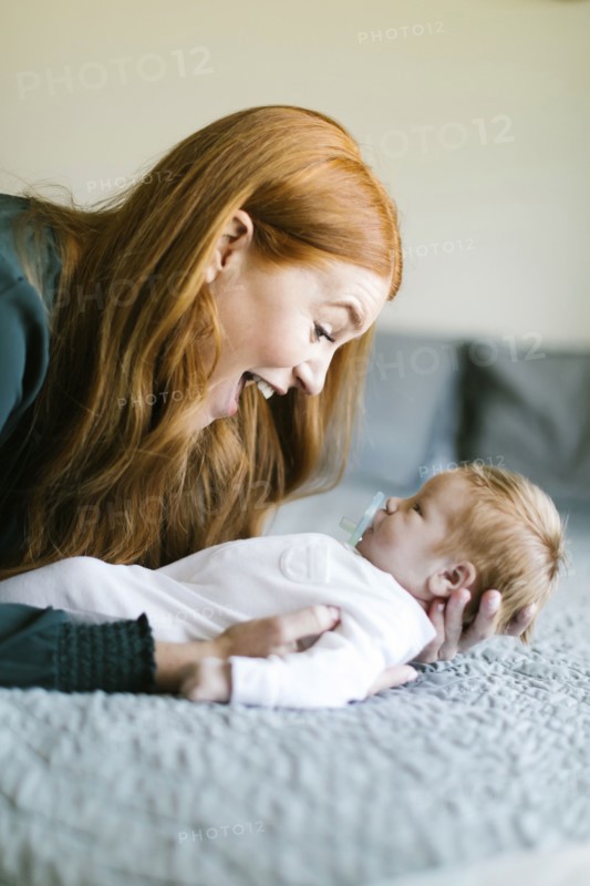 Woman holding her newborn son on bed