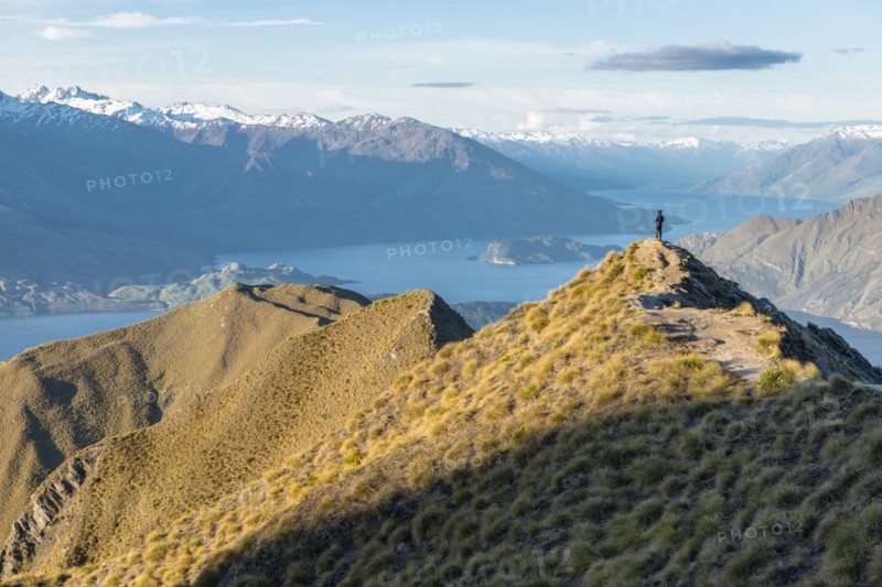 Man standing on mountain peak by Lake Wanaka, New Zealand