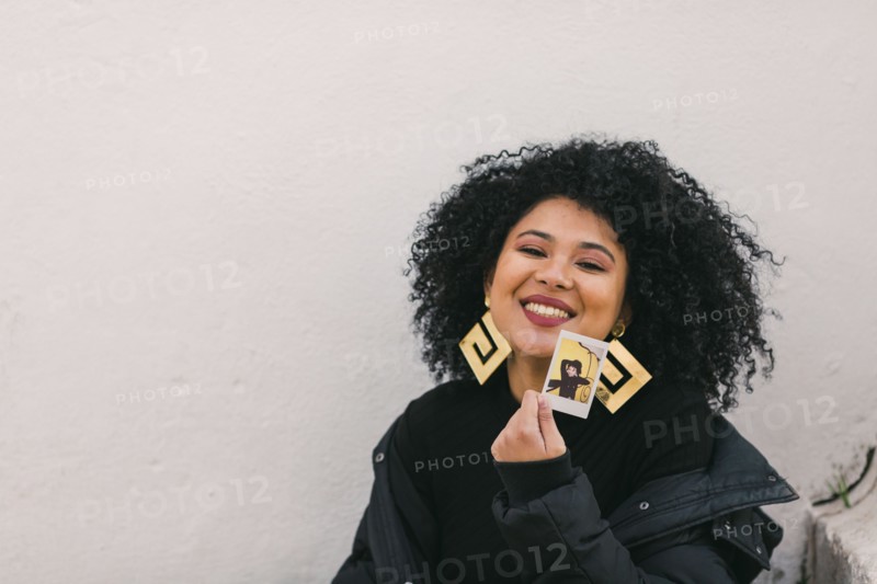 Smiling young woman holding photograph of herself