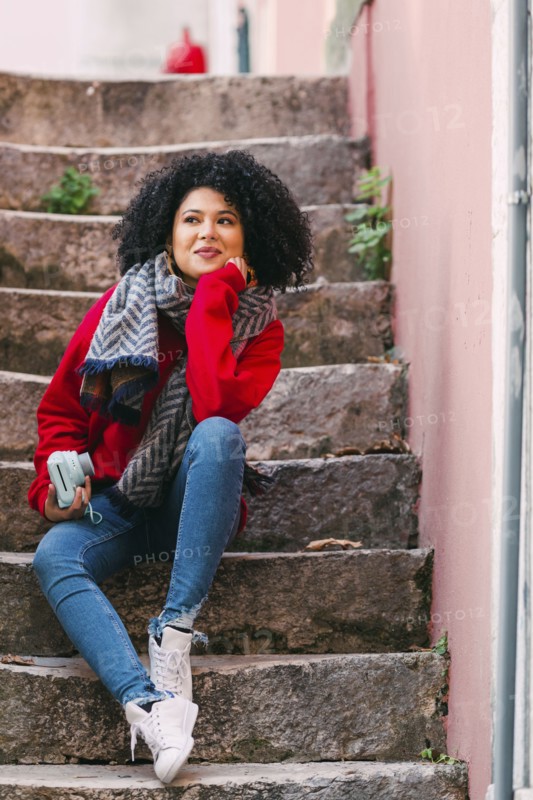 Young woman holding camera on staircase