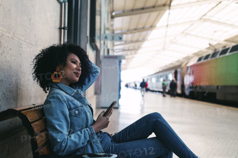 Young woman holding smart phone on railway platform