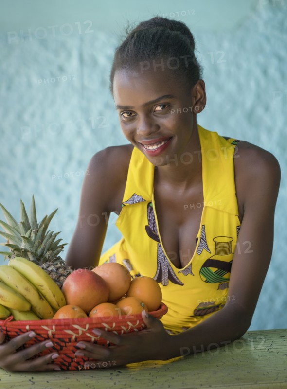 Smiling young woman holding fruit bowl