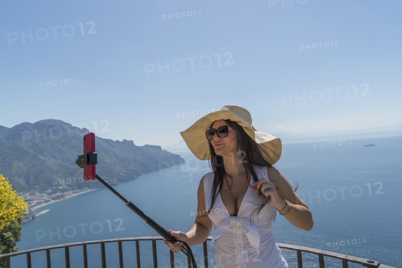 Woman using selfie stick by sea
