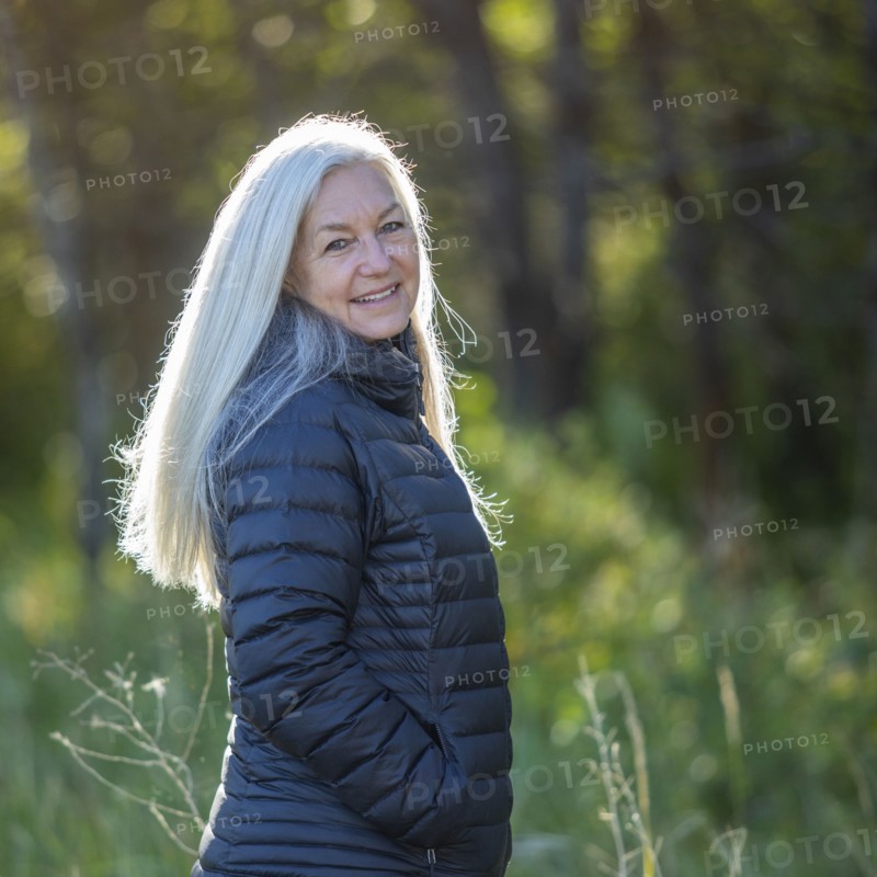 Mature woman wearing black jacket by forest