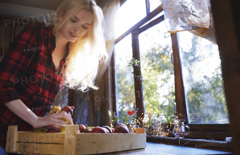 Woman with crate of apples by window