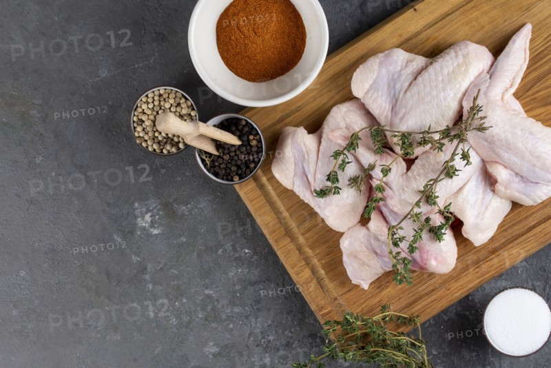 Raw chicken on cutting board with herb and spices